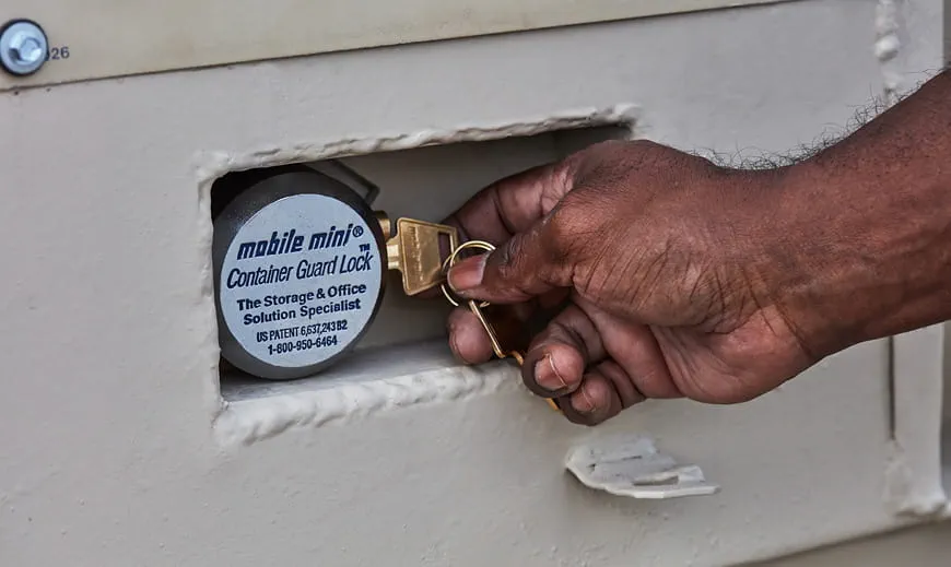 A workman's hand inserting a key into a storage container lock