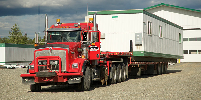 Truck carrying a mobile office trailer for delivery